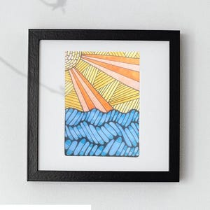 May include: A framed artwork titled Zenny Sunset measuring 3.5 inches by 2.5 inches. The print features a stylized sun with radiating yellow and orange lines above a sea of blue, rounded, overlapping shapes with dark outlines on a white background.