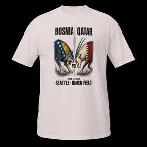 May include: White t-shirt with a graphic depicting a wolf and an oryx in a face-off, with the text "BOSNIA | QATAR" above and "JUNE 24, 2026 SEATTLE - LUMEN FIELD" below. The wolf is blue and yellow, the oryx red and white.