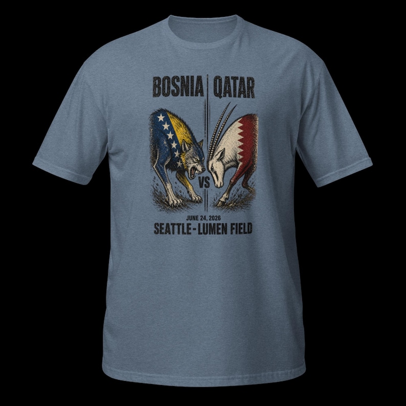 May include: A pale blue t-shirt with a graphic of a wolf and an oryx facing each other, with the text "BOSNIA | QATAR" above and "JUNE 24, 2020 SEATTLE - LUMEN FIELD" below. The wolf is colored with the Bosnian flag, and the oryx with the Qatar flag.