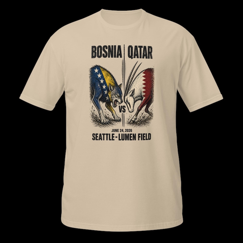 May include: A beige t-shirt with a graphic depicting a wolf and an oryx, symbolizing Bosnia and Qatar. The text "BOSNIA | QATAR" is above the image, with "VS" in the center. Below, it reads "JUNE 24, 2026 SEATTLE - LUMEN FIELD."