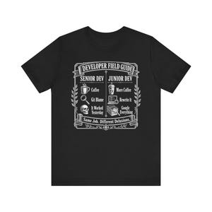 Könnte beinhalten: Ein schwarzes Kurzarm-T-Shirt mit einem weißen Grafikdruck mit dem Titel Developer Field Guide. Das Design vergleicht die Rollen Senior Dev und Junior Dev mit Symbolen für Kaffee, Git Blame, einen Totenkopf, einen Laptop, Bücher und den Text Same Job. Different Delusions.