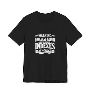 May include: Black t-shirt with white text. The text reads "WARNING DATABASE ADMIN MAY DISCUSS INDEXES at Dinner you've been warned". The shirt has a crew neck and short sleeves.