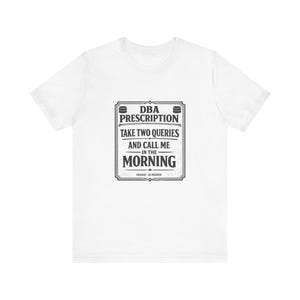 May include: White t-shirt with a black and gray graphic. The graphic reads "DBA Prescription: Take Two Queries and Call Me in the Morning." The text is framed within a rectangular border with decorative elements.