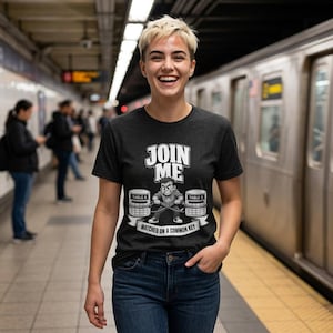 Może przedstawiać: Ciemnoszary t-shirt z krótkim rękawem z białym nadrukiem graficznym przedstawiającym osobę ciągnącą dwa stoły oznaczone jako TABLE A i TABLE B za pomocą liny. Tekst głosi JOIN ME oraz MATCHED ON A COMMON KEY. Koszulka ma okrągły dekolt.