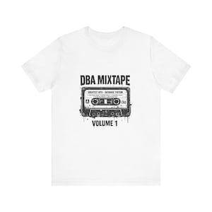 May include: White t-shirt featuring a black and gray graphic of a cassette tape with the text "DBA MIXTAPE VOLUME 1". The cassette tape design includes the text "GREATEST HITS - DATABASE EDITION".