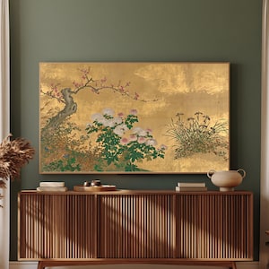May include: A rectangular wall art print featuring a gold leaf background with a detailed illustration of a gnarled tree branch with pink blossoms, clusters of white and pink chrysanthemums, and green grass blades, displayed in a thin wooden frame.