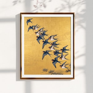 May include: A framed wall art print featuring a flock of dark blue and white swallows in flight against a textured gold leaf background. The birds are arranged in a diagonal formation, with stylized pine branches and water ripples at the bottom.