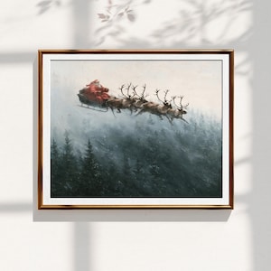 May include: A framed wall art print depicting a figure in a red suit riding in a dark sleigh pulled by a team of reindeer flying over a dense, misty forest of dark green pine trees under a pale, overcast sky during a light snowfall.