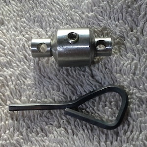 May include: A silver metal coupling with a small hole on each end and a small screw in the center. A black metal wrench is also pictured.