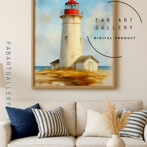 May include: A framed print of a lighthouse with a red top and white tower, set against a blue sky and ocean. The artwork is labeled "FAB ART GALLERY DIGITAL PRODUCT". The print is displayed above a white sofa with blue and striped pillows.