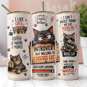 May include: Three stainless steel insulated tumblers with cat-themed designs. One tumbler says "I LIKE CATS..." with cat illustrations. Another says "INTROVERT, BUT WILLING TO DISCUSS CATS". The third says "BOSS CAT". Each tumbler has a straw.