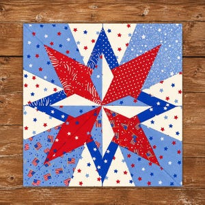 May include: A square, patriotic quilt block featuring a large star design. The star is composed of red and white patterned fabrics, including polka dots and flag motifs, set against blue and white backgrounds. The block is on a wooden surface.
