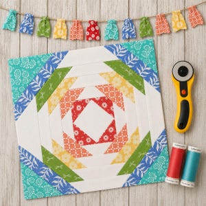 May include: A colorful quilt block with a pineapple design, featuring red, orange, yellow, green, and blue patterned fabrics. A yellow rotary cutter and spools of red and teal thread are next to the block. A garland of mini fabric skirts hangs above.