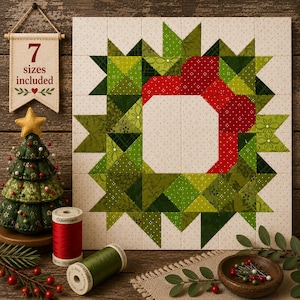 May include: A square quilt block featuring a wreath pattern in shades of green and red on a cream background with small dots. A fabric banner with the text 7 sizes included, a green fabric Christmas tree, and two spools of thread are present.