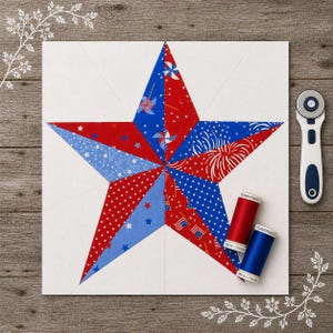 May include: A patriotic star quilt block with red, white, and blue patterned fabrics. The star is centered on a white square, with spools of red and blue thread and a rotary cutter nearby. The fabrics feature stars, fireworks, and flag designs.