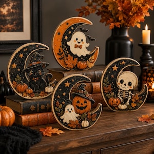 May include: Four crescent moon-shaped decorations featuring Halloween themes. One shows a black cat in a witch hat, another a ghost with a bow tie, one a skeleton, and one a jack-o'-lantern with a ghost, all accented with autumn leaves and pumpkins.