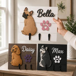 Puede incluir: Tres organizadores de pared rectangulares de madera con ilustraciones de perros. Un tablero blanco muestra un bulldog francés y el nombre Bella. Un tablero marrón muestra un spaniel y Daisy. Un tablero negro presenta un husky y el nombre Max.