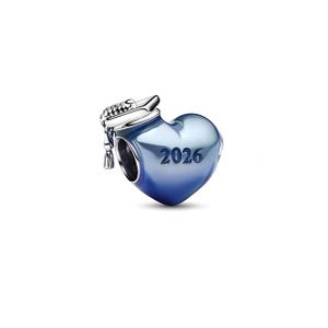 Może przedstawiać: Urok w kształcie serca z czapką absolwenta i rokiem "2026" wygrawerowanym na przodzie. Urok ma gradientowy niebieski kolor i srebrną czapkę absolwenta. Urok jest prawdopodobnie wykonany z metalu.