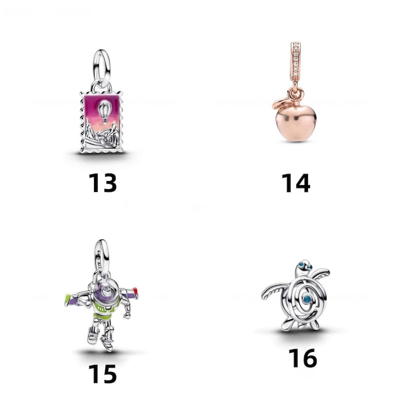 May include: Four silver and rose-gold tone charms labeled 13 through 16. Charm 13 is a rectangular stamp with a hot air balloon. Charm 14 is a rose-gold apple. Charm 15 is a colorful space ranger figure. Charm 16 is a silver sea turtle charm.