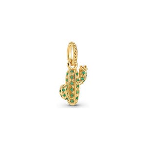 Pu&ograve; includere: Un ciondolo a forma di cactus dorato con accenti di pietre preziose verdi. Il ciondolo ha una superficie strutturata e un anello per attaccarlo a un braccialetto o una collana. Il design del cactus include un corpo principale e un braccio laterale, entrambi adornati con pietre verdi.