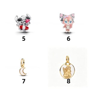 May include: Four silver and gold-tone metal charms labeled 5 through 8. Charm 5 is a silver Stitch figure with black sunglasses and a red and white life ring. Charm 6 is a pink and white fox figure. Charm 7 is a gold crescent moon. Charm 8 is a gold circular pendant with a white enamel background and a raised gold cherub figure.