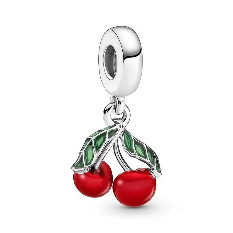 Pu&ograve; includere: Un charm in argento con due ciliegie rosse lucide e foglie verdi. Il charm ha un anello nella parte superiore per il fissaggio a un braccialetto o una collana. Le ciliegie sono dettagliate.
