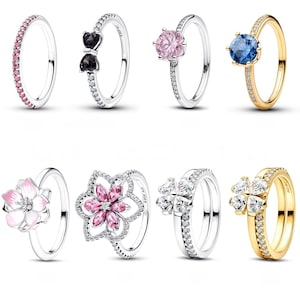 May include: Collection of rings featuring various designs. Rings include a band with pink stones, a bow with black stones, a pink gemstone, a blue gemstone, a flower with pink petals, a flower with pink stones, and two rings with clear stones.