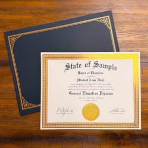 May include: A cream-colored General Education Diploma certificate with black text and a gold foil border, featuring a gold embossed seal. It is accompanied by a dark navy blue folder with a matching gold foil decorative border and corner accents.