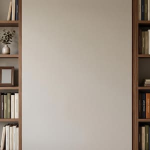 Puede incluir: Dos estanterías de madera llenas de libros de varios colores y tamaños. Las estanterías están dispuestas a ambos lados de una pared de color neutro. Objetos decorativos como un pequeño jarrón, un marco de fotos y una planta en maceta se colocan en las estanterías.