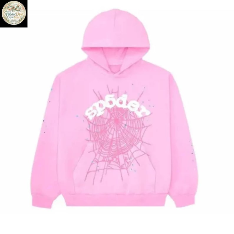 Puede incluir: Una sudadera con capucha rosa claro con capucha y bolsillo delantero. La parte delantera de la sudadera presenta la palabra "spider" en blanco, encima de un dise&ntilde;o de telara&ntilde;a. Las mangas tienen peque&ntilde;os adornos dispersos.