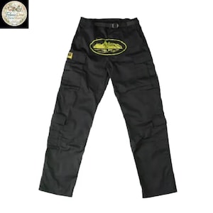 May include: Black cargo pants with multiple pockets and a belt. A yellow graphic of a building is on the front. The pants have a straight leg design and are made of a durable material.