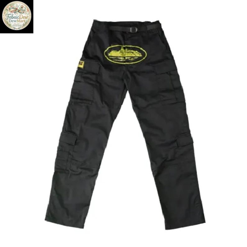 May include: Black cargo pants with multiple pockets and a belt. A yellow graphic of a building is on the front. The pants have a straight leg design and are made of a durable material.