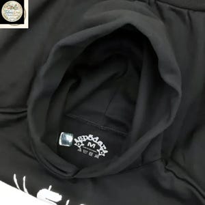 Pode incluir: Moletom preto com capuz e etiqueta interna. A etiqueta tem a palavra "spoder" e a letra "M" impressas. O moletom &eacute; feito de um material macio e &eacute; adequado para uso casual.