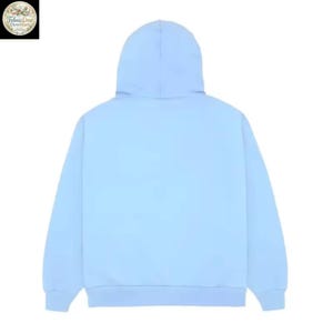 May include: A light blue hoodie with a hood. The back view of the sweatshirt is shown, with the hood up. The hoodie is made of a soft material and is a solid color.