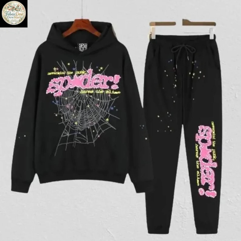 May include: Black hooded sweatshirt and matching sweatpants set. The sweatshirt features a pink "spider!" graphic with a spiderweb design. The sweatpants have a drawstring waist and a matching graphic on the leg.