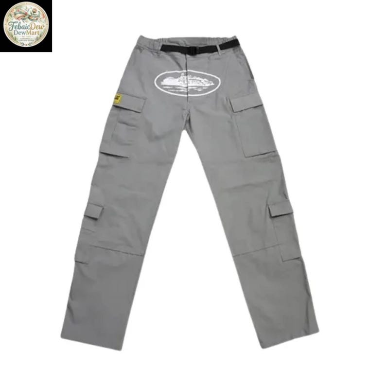 May include: Gray cargo pants with multiple pockets and a black belt. An oval graphic with a white illustration of a building is centered on the front. A small yellow patch is on the left pocket.