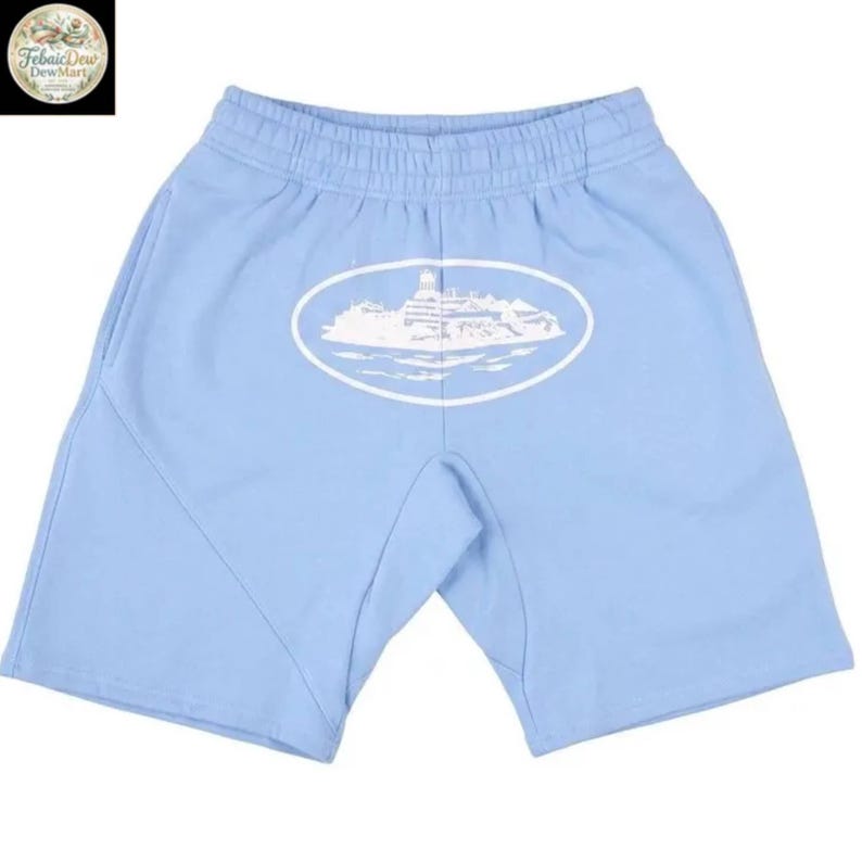 Puede incluir: Pantalones cortos de color azul claro con un dise&ntilde;o gr&aacute;fico ovalado blanco de un edificio en la parte delantera. Los pantalones cortos tienen cintura el&aacute;stica y bolsillos. Los pantalones cortos est&aacute;n hechos de un material suave.