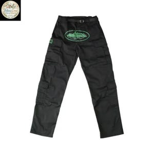 May include: Black cargo pants with multiple pockets and a belt. A green oval design with a landscape is centered on the front. The pants have a small green square patch on the left pocket. The pants are made of a durable material.