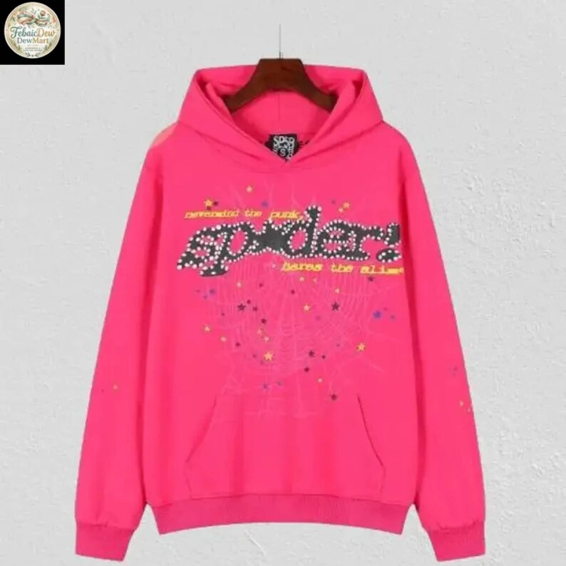 May include: A bright pink hoodie with a front pocket and a hood. The front features the word "sp5der" in a stylized font, with additional text and a spiderweb design. The hoodie is made of a soft material.