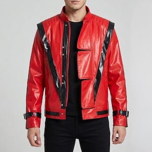 Puede incluir: Chaqueta de cuero roja con detalles en negro. Cuenta con cuello alto, hombros acolchados y rayas negras en los laterales y mangas. Cierre de botones y hebillas en las muñecas. Prenda de vestir elegante.