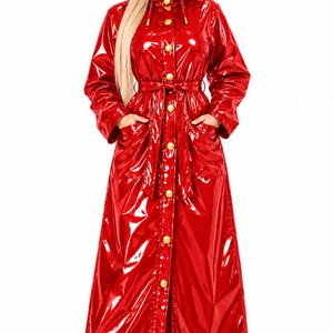 Puede incluir: Un impermeable largo de color rojo brillante con capucha, mangas largas y cierre frontal de botones. El abrigo incluye un cinturón a juego para anudar en la cintura, dos bolsillos delanteros y un acabado brillante y reflectante.