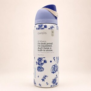 Pu&ograve; includere: Una borraccia Owala bianca con un motivo floreale blu e un coperchio azzurro. L'etichetta riporta: Hi there. I'm leak proof. I'm insulated. And I have a built-in straw. I know. Where have I been all your life? 32 oz. (945 ml).