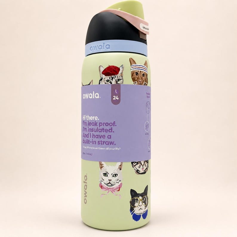 May include: A light green Owala water bottle with a black and light blue lid, featuring a wrap-around purple label with cat illustrations and text that reads: Hi there. I'm leak proof. I'm insulated. And I have a built-in straw. 24 oz (710 ml).