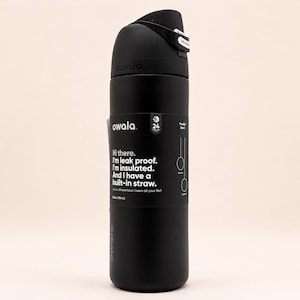 May include: A matte black Owala water bottle with a 24 oz capacity. The bottle features a black lid with a built-in straw and a black label with white text that reads: Hi there. I'm leak proof. I'm insulated. And I have a built-in straw.