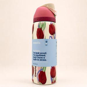 May include: An Owala 32 oz. insulated water bottle with a cream-colored base featuring a red tulip pattern. The lid is dark pink with a beige flip-top. A light blue paper band wraps around the center with the text: Hi there. I'm leak proof.