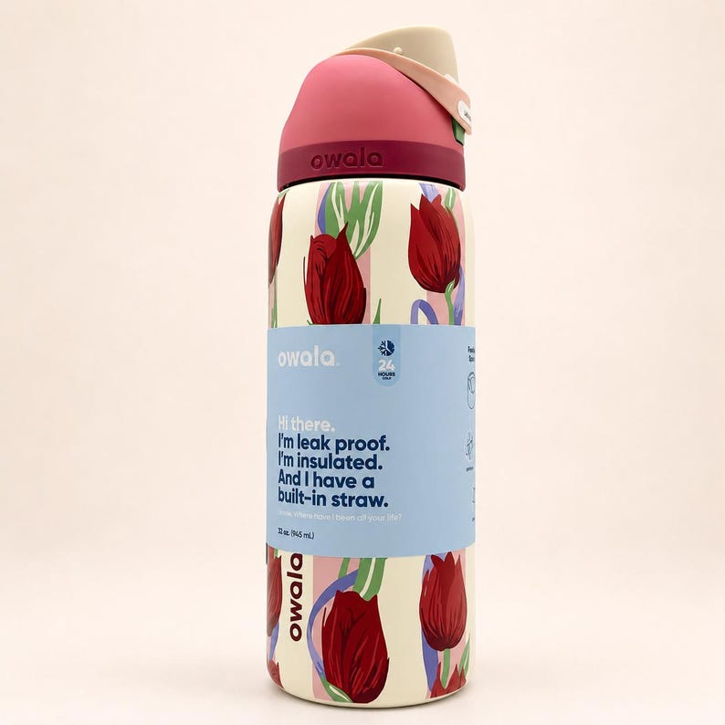 May include: An Owala 32 oz. insulated water bottle with a cream-colored base featuring a red tulip pattern. The lid is dark pink with a beige flip-top. A light blue paper band wraps around the center with the text: Hi there. I'm leak proof.