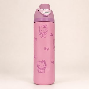 May include: A light pink water bottle featuring a repeating pattern of Hello Kitty characters and small bows in a darker pink outline. The bottle has a purple lid with a flip-top mechanism that includes a white tab labeled Lift to Unlock.