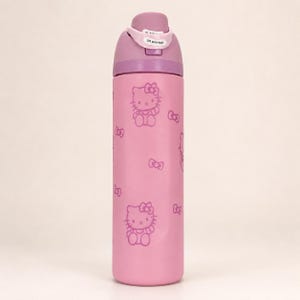 K&ouml;nnte beinhalten: Eine hellrosa Trinkflasche mit einem wiederkehrenden Muster aus Hello Kitty-Figuren und kleinen Schleifen in dunkelrosa Umrissen. Die Flasche hat einen violetten Deckel mit Klappmechanismus und einer wei&szlig;en Lasche mit der Aufschrift Lift to Unlock.