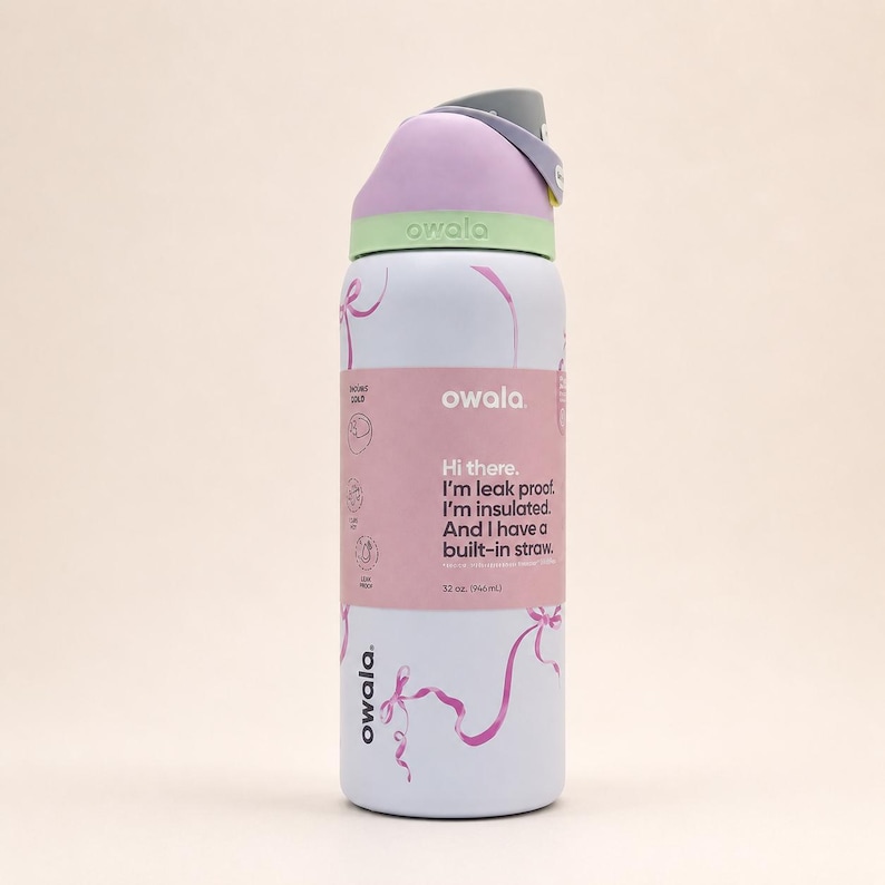 Pu&ograve; includere: Una borraccia Owala bianca con capacit&agrave; di 946 ml, dotata di coperchio viola chiaro e verde, manico grigio e grafiche a nastro rosa. Un'etichetta riporta: Hi there. I'm leak proof. I'm insulated. And I have a built-in straw. 32 oz. (946 mL).