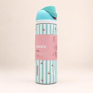 May include: A 24-ounce Owala water bottle featuring a light blue and white vertical striped pattern with small red cherry icons. The bottle has a light blue lid and a pink product label wrapped around the center with the text Owala and 24 oz (710 ml).